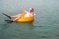 Teenage boy in flippers, Santa hat and on inflatable circle swims and rests on sea waves