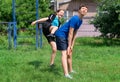 Teenage boy and girl exercising outdoors and having fun, sports ground in the yard, the girl hits the guy`s ass with her foot, Royalty Free Stock Photo