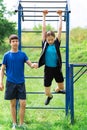 Teenage boy and girl exercising outdoors, sports ground in the yard, they posing at the horizontal bar, healthy lifestyle Royalty Free Stock Photo