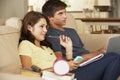 Teenage Boy And Girl Sitting On Sofa At Home Doing Homework Using Laptop Computer Whilst Holding Mobile Phone Royalty Free Stock Photo