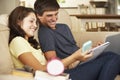 Teenage Boy And Girl Sitting On Sofa At Home Doing Homework Using Laptop Computer Whilst Holding Mobile Phone Royalty Free Stock Photo