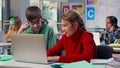 Teenage boy and girl study on laptop together sitting at desk in classroom Royalty Free Stock Photo