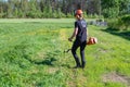 Teenage Boy going to cut grass with handheld gasoline lawn mower. He wears eye and ear protection headphones. Health and safety Royalty Free Stock Photo