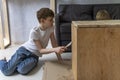 Teenage boy helps restore an old table. Child paints wooden pedestal with brush. Side view