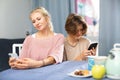 Teenage boy and his mother sitting at home table with smartphones Royalty Free Stock Photo