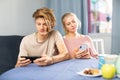 Teenage boy and his mother sitting at home table with smartphones Royalty Free Stock Photo