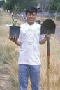 A teenage boy holding a plant and a shovel during Earth Day participation