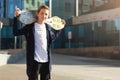 Teenage boy holding skateboard outdoors, standing on the street and looking at camera. Copy space Royalty Free Stock Photo