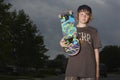 Teenage boy (13-15) holding skateboard outdoors portrait close up