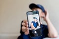 teenage boy holding a smart phone in front of his face at home, taking selfies with his smartphone, digital display on Royalty Free Stock Photo