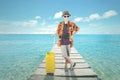 Teenage boy holds a luggage on the dock bridge