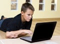 Teenage boy and laptop on floor