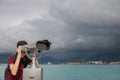 Teenage boy looking through mounted binoculars near sea. Space for text Royalty Free Stock Photo