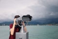 Teenage boy looking through mounted binoculars near sea. Space for text Royalty Free Stock Photo