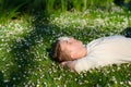 Teenage boy lying on the meadow full of white flowers in summer