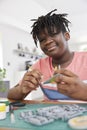 Portrait Of Teenage Boy Building Model Aeroplane From Kit On Table At Home