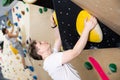 Teenage boy climbs steep artificial wall in sports complex and trains endurance Royalty Free Stock Photo