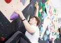 Teenage boy climbs steep artificial wall in sports complex and trains endurance Royalty Free Stock Photo