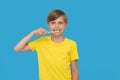 Teenage boy without one teeth with toothbrush brushing his teeth on blu background