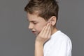 Teenage boy with pained expression holding his sore ears Royalty Free Stock Photo