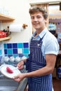 Teenage Boy With Part Time Job Washing Up In Coffee Shop Royalty Free Stock Photo