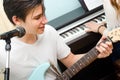 Teenage boy playing electric guitar and singing while girl plays Royalty Free Stock Photo