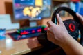 Teenage boy playing on truck driving simulator in front of a computer with glowing keyboard, focus on the boys hand