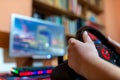 Teenage boy playing on truck driving simulator in front of a computer with glowing keyboard