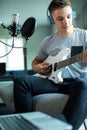 Teenage Boy Playing Guitar And Recording Music Onto Laptop At Home Royalty Free Stock Photo