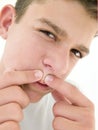 Teenage boy popping zit on face