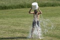 Teenage boy pouring bucket of cold water over his head outdoors. Ice water challenge. Cold water therapy benefits Royalty Free Stock Photo