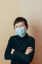 A teenage boy in a protective mask has crossed his arms and keeps curfews during restrictions imposed due to the outbreak of the v