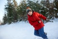 Teenage boy in red puffed jacket and knitted hat has fun in the winter in the woods. Child pulls sled