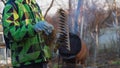 A teenage boy removes dry grass from a rake in the spring. Spring cleaning of the garden with a rake Royalty Free Stock Photo