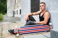 Teenage boy with scateboard sitting on stone path in front of old building. Royalty Free Stock Photo