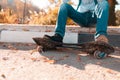 A teenage boy sits on a step with his feet on a skateboard. Street in the background. Close up and copy space Royalty Free Stock Photo