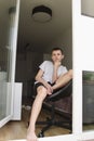 A teenage boy is sitting in an open door and is sad, looking in front of him Royalty Free Stock Photo