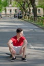 Teenage boy sitting on skateboard in the middle of street Royalty Free Stock Photo