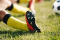 Teenage Boy Sitting and Stretching on Sports Grass Field. Soccer Ball in the Background Royalty Free Stock Photo