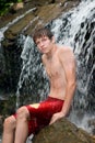 Teenage boy sitting in waterfall. Royalty Free Stock Photo