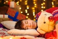 Teenage boy sleeping in new year or christmas decoration. Holiday lights, gifts and christmas tree decorated with toys Royalty Free Stock Photo