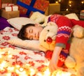 Teenage boy sleeping in new year or christmas decoration. Holiday lights, gifts and christmas tree decorated with toys Royalty Free Stock Photo