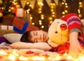 Teenage boy sleeping in new year or christmas decoration. Holiday lights, gifts and christmas tree decorated with toys Royalty Free Stock Photo