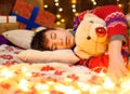 Teenage boy sleeping in new year or christmas decoration. Holiday lights, gifts and christmas tree decorated with toys