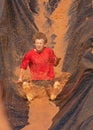 Teenage boy sliding down water slide in a mud run Royalty Free Stock Photo