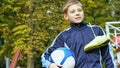 Smiling teenage boy with a soccer ball in his hand and soccer boots on the shoulder against the background of the Royalty Free Stock Photo