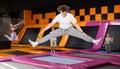 Teenage boy in sport clothes high jumping in trampoline arena