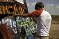 Teenage Boy Spray Painting a Car