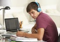 Teenage Boy Studying At Desk In Bedroom Wearing Headphones Royalty Free Stock Photo