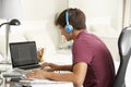 Teenage Boy Studying At Desk In Bedroom Wearing Headphones Royalty Free Stock Photo